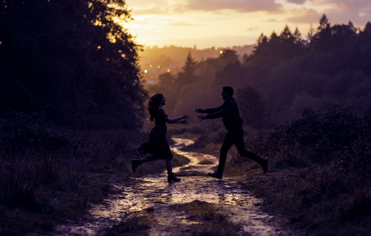 Silhouette of a man running towards a woman at sunset, representing signs he will return.