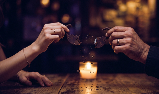Hands separating a breaking lock over candlelight, symbolizing the release of a karmic relationship pattern