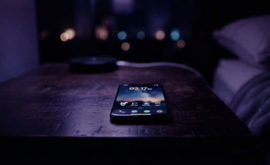 Smartphone on a wooden table at night, symbolizing the question, why isn't he texting me back.
