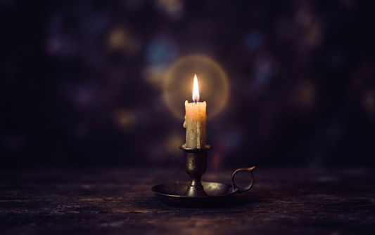 Candle illuminating darkness, symbolizing contemplation for left eye twitching spiritual meaning.
