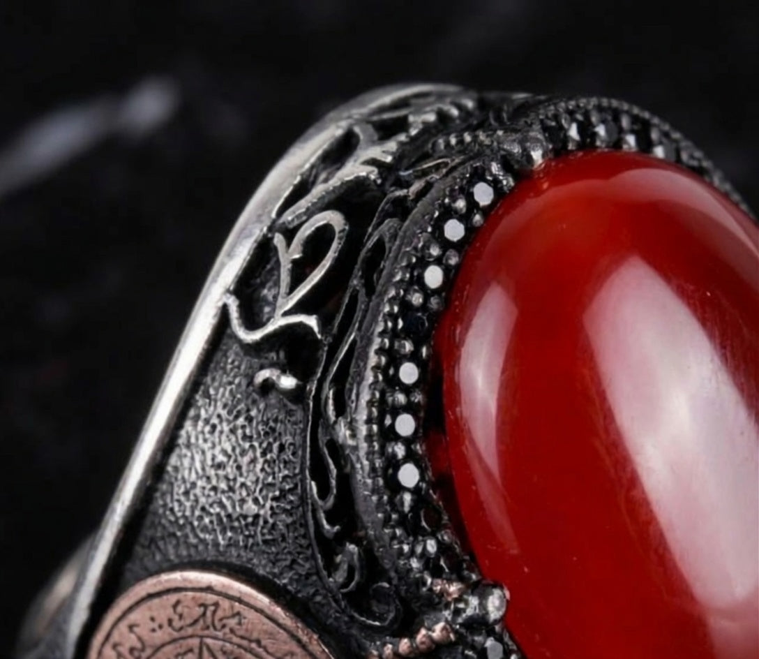Close-up of oxidized sterling silver metalwork and black accents around red agate